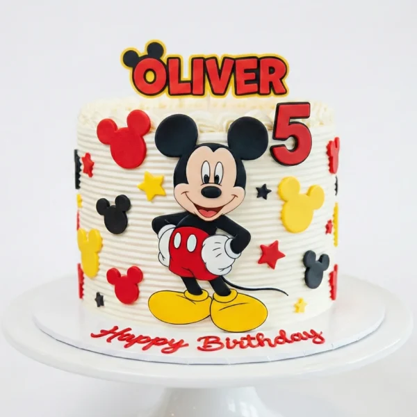 Custom Mickey Mouse birthday cake featuring a fondant Mickey topper, colorful star decorations, and the number 5 on a white frosted base, displayed on a cake stand at Winny's Bakery Dubai.