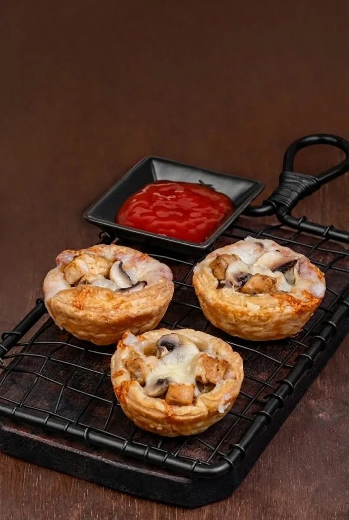 Chicken mushroom pies in flaky pastry with melted topping, served with ketchup dip.