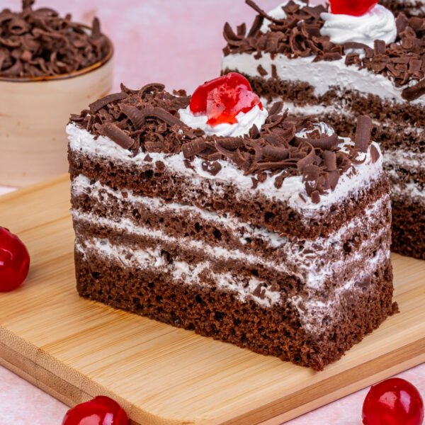 Chocolate Black Forest pastry slice with whipped cream, chocolate shavings, and cherry on top