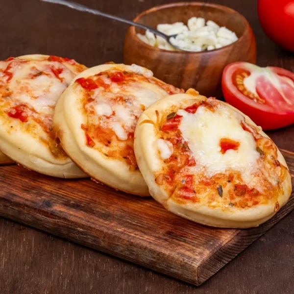 Mini cheese pizzas topped with tomato sauce and melted cheese on a wooden board.