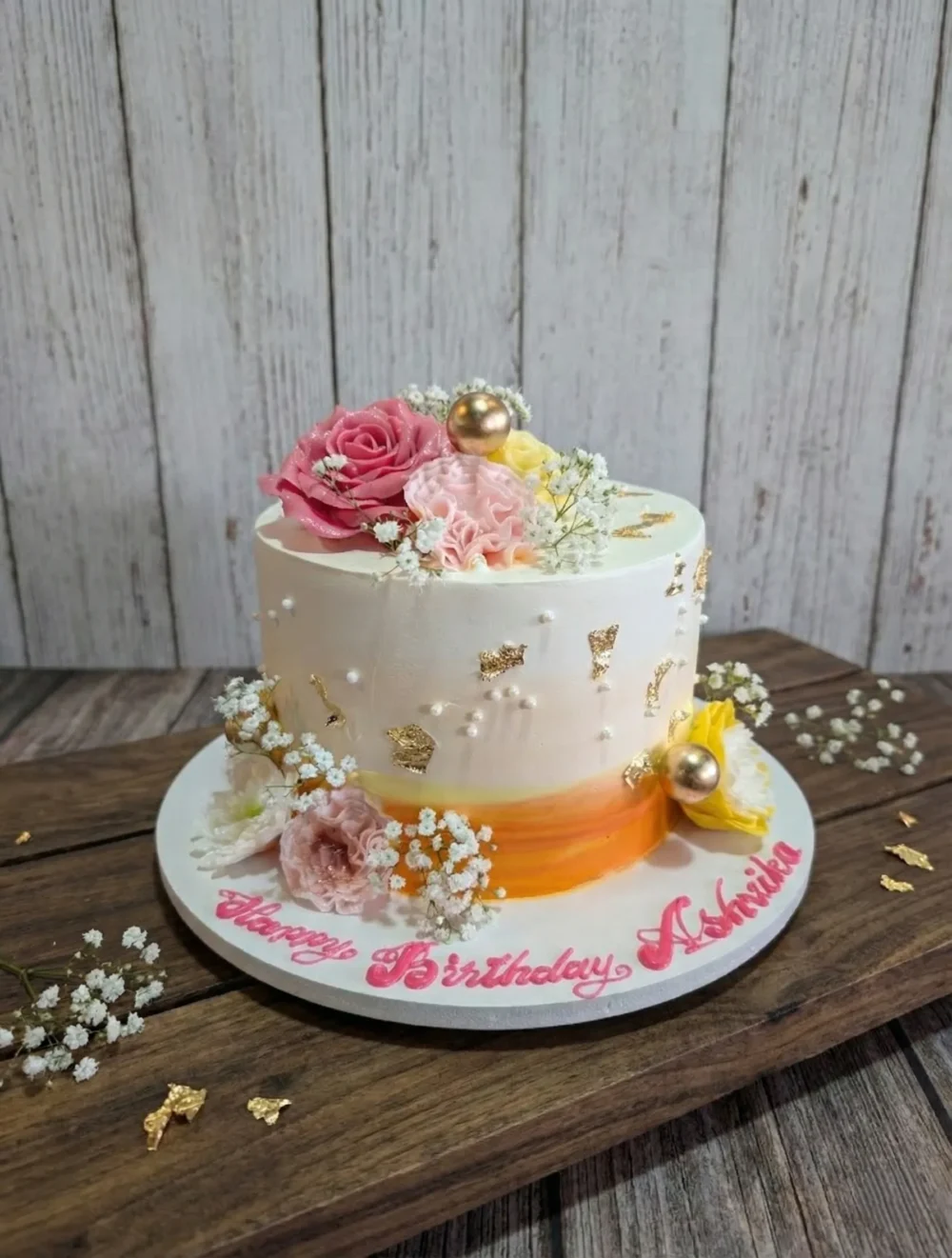 Blush floral celebration cake with peach and ivory buttercream, gold accents, and fresh floral detailing
