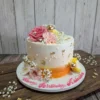 Blush floral celebration cake with peach and ivory buttercream, gold accents, and fresh floral detailing